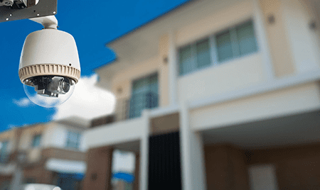 A white security camera in front of a house.